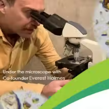 Person using a microscope with text overlay 'Under the microscope with Co-founder Everest Holmes'.